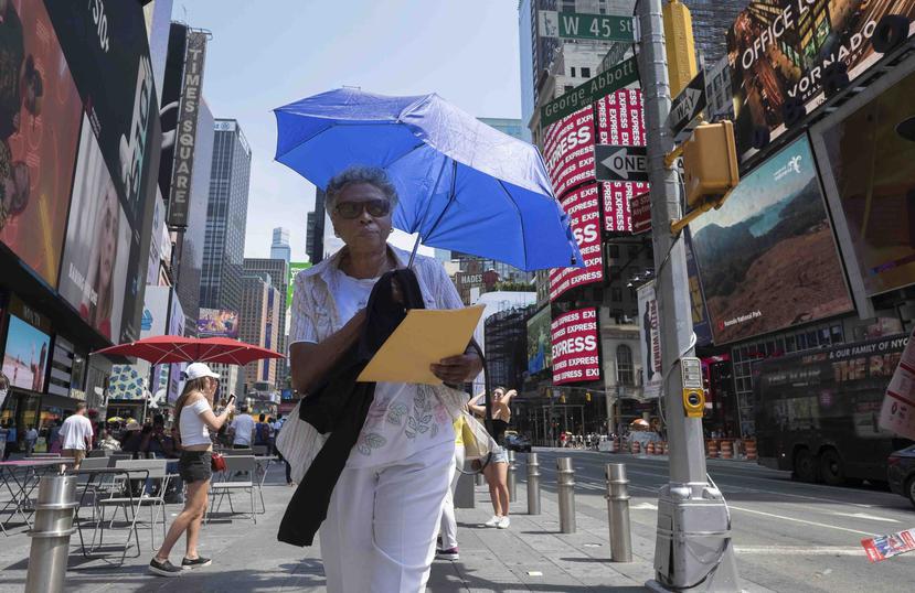 Una señora usa una sombrilla para protegerse del sol mientras camina en Times Square, en la ciudad de Nueva York. (AP/Jonathan Carroll)