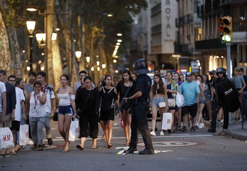 Un grupo de gente se desplaza entre el despliegue policial en el lugar del atentado ocurrido por la tarde en Las Ramblas. (EFE)