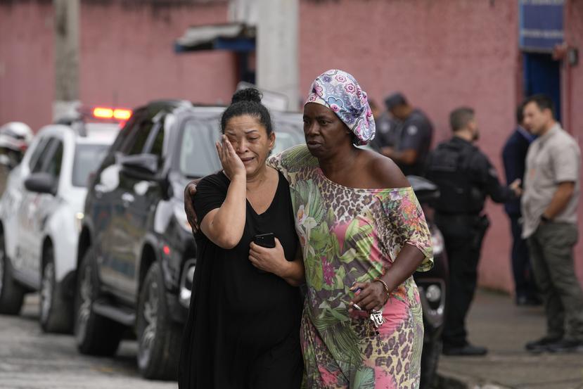 Silvia Palmieri (izquierda), quien es madre de una maestra que sobrevivió a un ataque a puñaladas en la escuela Thomazia Montorosale es consolada por una amiga en Sao Paulo, Brasil.