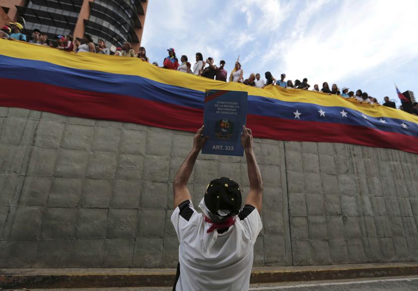 Un manifestante antigubernamental sostiene en alto una imagen de la Constitución de Venezuela durante un homenaje a los fallecidos en las protestas contra el presidente del país, Nicolás Maduro. (AP)
