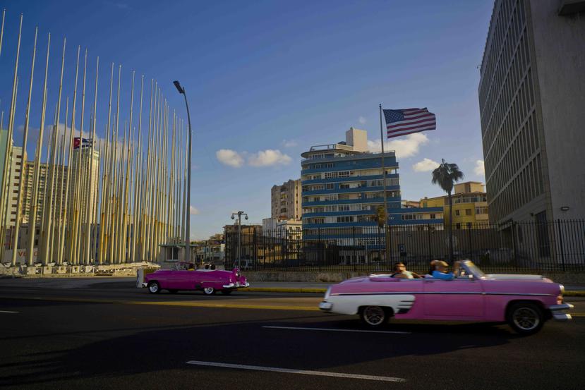 En esta fotografía de archivo del 12 de enero de 2017, turistas pasean sobre un clásico convertible estadounidense frente a la embajada de Estados Unidos en La Habana, Cuba. (Archivo / AP)