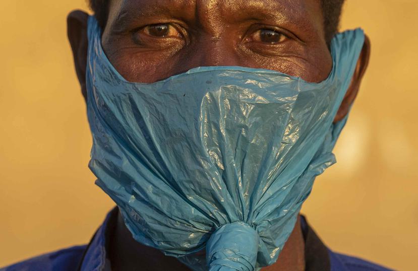 Un hombre usa una bolsa de plástico en la cara como medida de precaución contra la propagación del coronavirus al este de Johannesburgo, Sudáfrica. (AP)