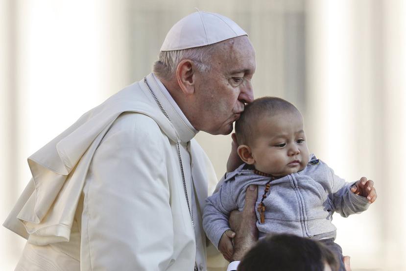 El papa Francisco besa a un niño a su llegada a la Plaza de San Pedro a bordo del papamóvil para su audiencia general semanal, en el Vaticano. (AP / Gregorio Borgia)