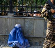 Foto de archivo de una mujer afgana vestida con burka que pide limosna mientras los talibanes hacen guardia en un lugar público en Kabul.