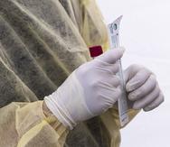 Un doctor sostiene una prueba de coronavirus.