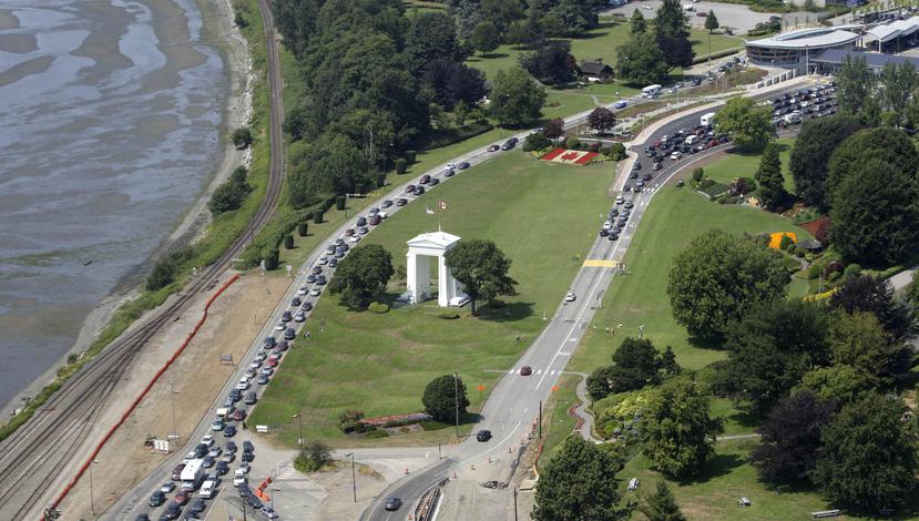 En esta fotografía de archivo del 24 de julio de 2009, varios vehículos hacen fila para cruzar hacia Estados Unidos, a la izquierda, y a Canadá, a la derecha, en la localidad canadiense de Boundary Bay, frente a Blaine, Washington. (AP)