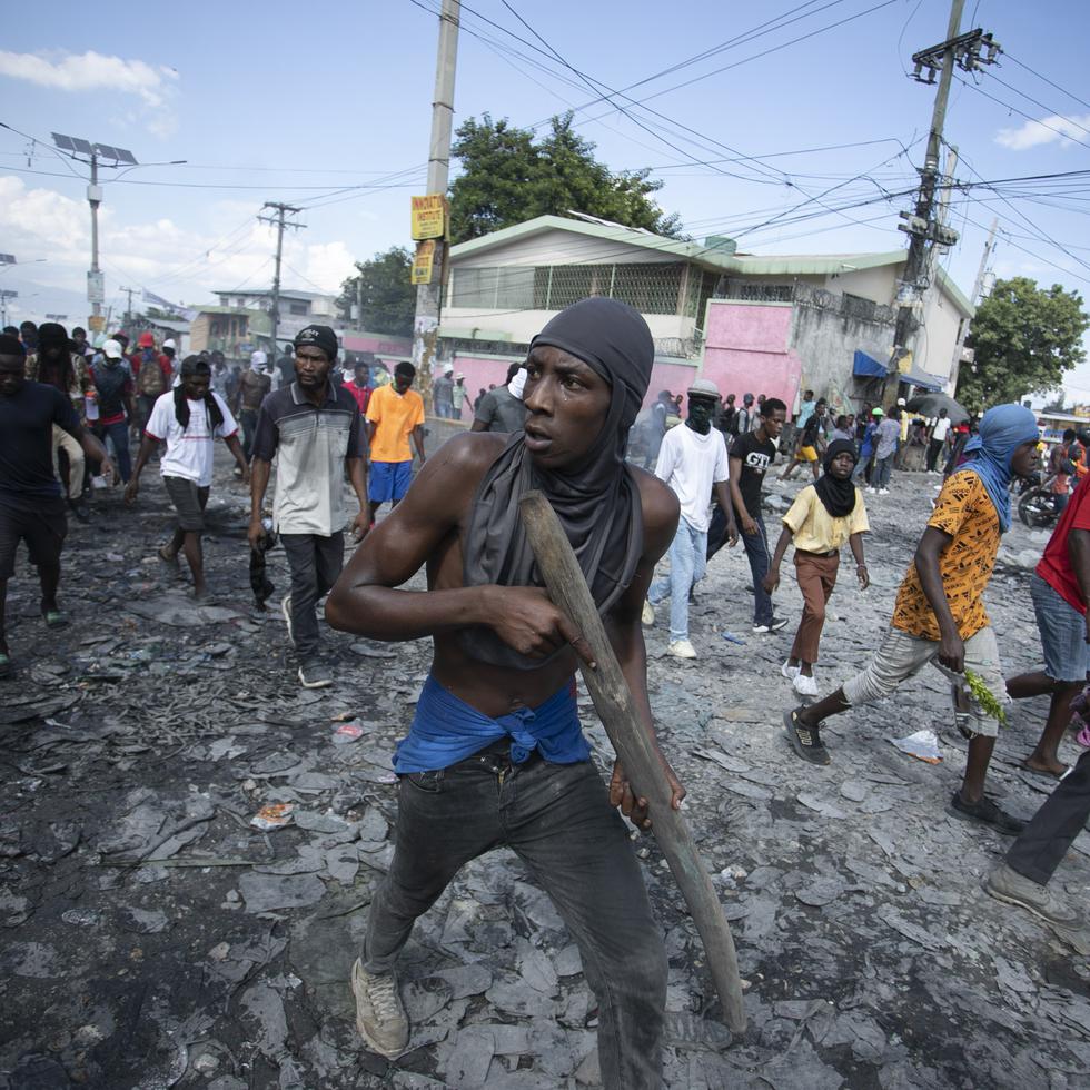Un manifestante lleva un trozo de madera que simula un arma durante una protesta en la que se exigió la renuncia del primer ministro Ariel Henry en el área de Petion-Ville de Puerto Príncipe, Haití, el 3 de octubre de 2022. (AP Foto/Odelyn Joseph)