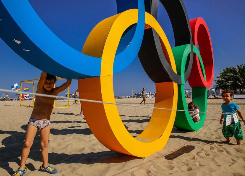 Niños juegan junto a los anillos olímpicos, creados en material reciclado, en la playa de Copacabana en Río de Janeiro (Brasil). (EFE)