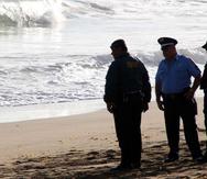 Tres agentes de la Policía investigan un ahogamiento en la playa. (GFR Media)