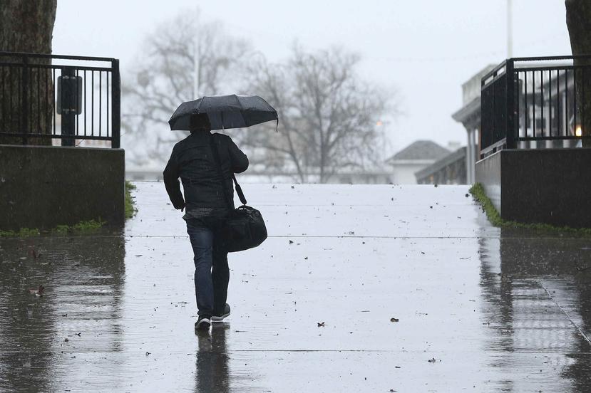 Un hombre camina bajo su paraguas cuando una tormenta pasaba en Sacramento, California. (AP)