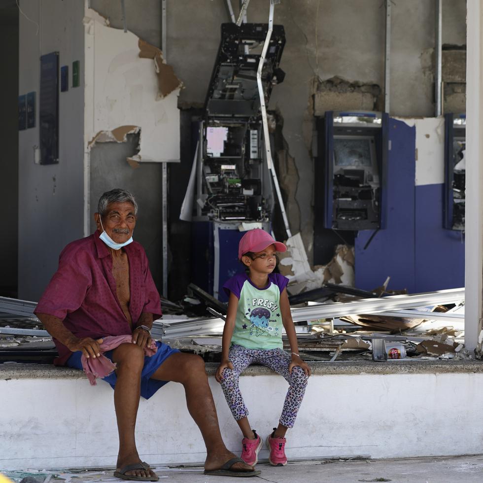 Residentes sentados delante de una entidad bancaria, sin ventanales y con los cajeros destrozados, dos días después del paso del devastador huracán Otis, de categoría 5, en Acapulco, México.