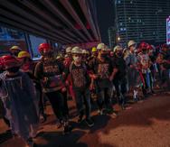 Activistas prodemocracia crean una cadena humana ante las barricadas policiales durante su marcha hacia la Casa de Gobierno, la oficina del primer ministro, durante una protesta en Bangkok, Tailandia, el miércoles 21 de octubre de 2020.