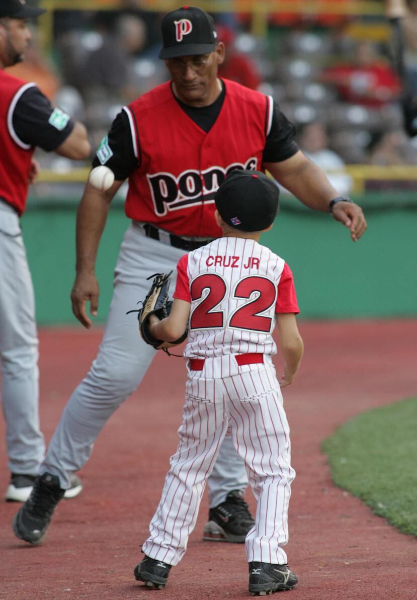 Cirilo Cruz, de frente, juega con su sobrino nieto  Trei en un partido del béisbol invernal en el 2004. (Archivo)