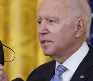 El presidente Joe Biden sostiene una mascarilla mientras habla sobre unas medidas nuevas relacionadas con el coronavirus para los trabajadores federales.