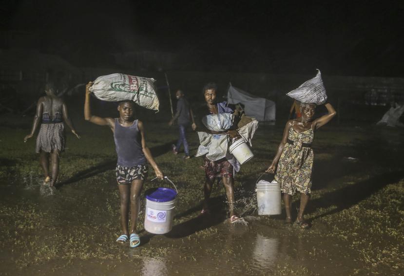 Las personas afectadas por el terremoto del sábado caminan bajo la lluvia de la tormenta tropical Grace en un campo de refugiados en Les Cayes, Haití,.