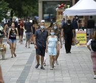 Pedestrians wear masks out of concern for the coronavirus, Sunday, June 28, 2020, while walking along a sidewalk, in Boston. (AP Photo/Steven Senne)