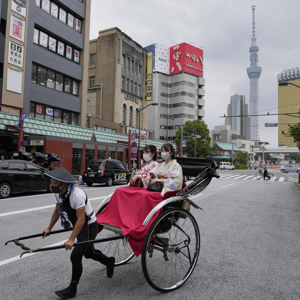 Un bicitaxi lleva a pasajeros por el distrito de Asakusa, en Tokio, el 22 de junio de 2022.
