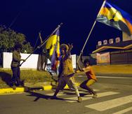 ARCHIVO - En esta fotografía de archivo del 4 de noviembre de 2018, activistas independentistas celebran en las calles de Numea, capital de Nueva Caledonia, mientras ondean la bandera indígena de los kanaks. (AP Foto/Mathurin Derel, archivo)