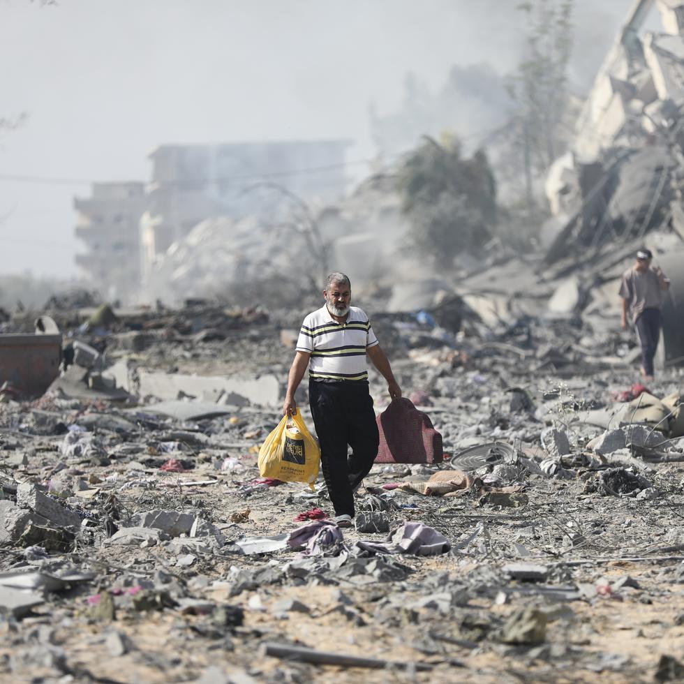 Palestinos caminan junto a edificios destruidos en un bombardeo israelí sobre al-Zahra, en las afueras de la Ciudad de Gaza.