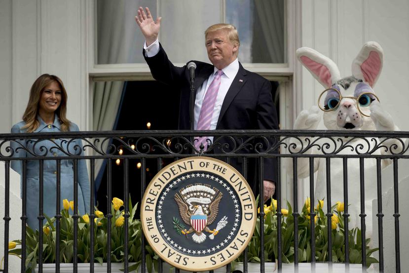 El presidente Donald Trump, acompañado por el conejito de Pascua y la primera dama Melania Trump, saluda desde el Balcón  Truman en la Casa Blanca en Washington, el lunes 22 de abril de 2019, durante el Anuario de Huevos de Pascua de la Casa Blanca. (AP /