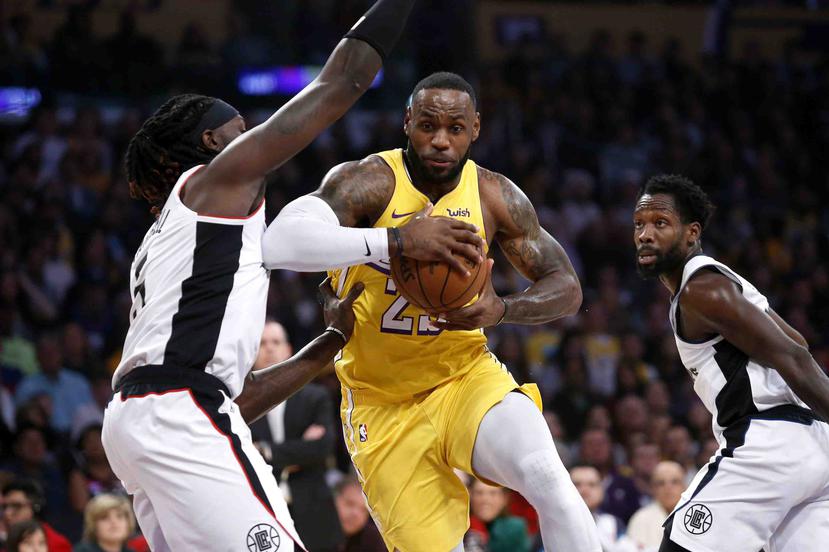 LeBron James (23), de los Lakers de Los Ángeles, se abre paso a la canasta ante Montrezl Harrell, izquierda, de los Clippers de Los Ángeles. (AP/Ringo H.W. Chiu)