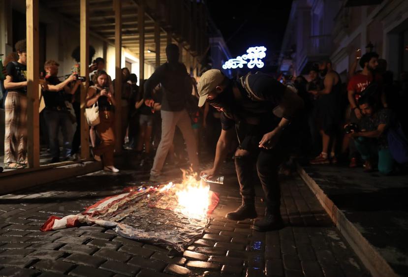 Un manifestante quema una bandera en una de las calles de San Juan.