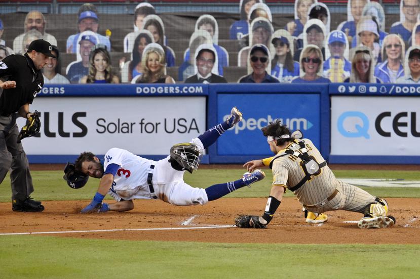 El jugador de los Dodgers de Los Ángeles, Chris Taylor (centro) intenta anotar mientras el receptor de los Padres, Austin Hedges (derecha) lo retira del juego.