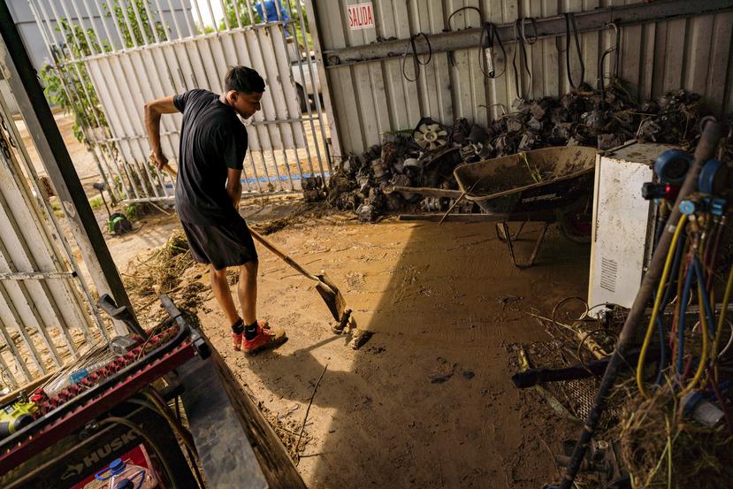 Un joven limpia el fango que se acumuló en el establecimiento Los Hermanos Auto Air en Salinas.