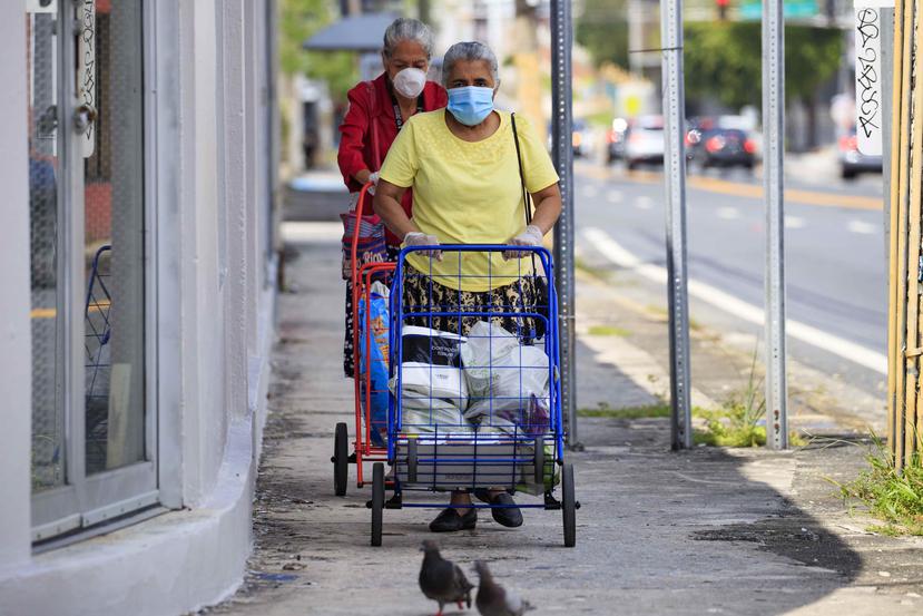 Ciudadanas caminan por las aceras en la avenida Ponce de León en San Juan luego de realizar compras.