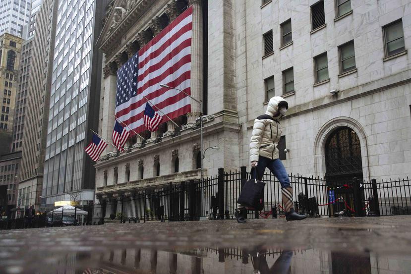Una persona con máscara camina frente al edificio de la Bolsa de Valores de Nueva York, en la Gran Manzana, hoy jueves. (AP Photo/Kevin Hagen)