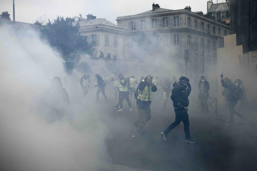Manifestantes corren entre gas lacrimógeno rociado por la policía. (AP)