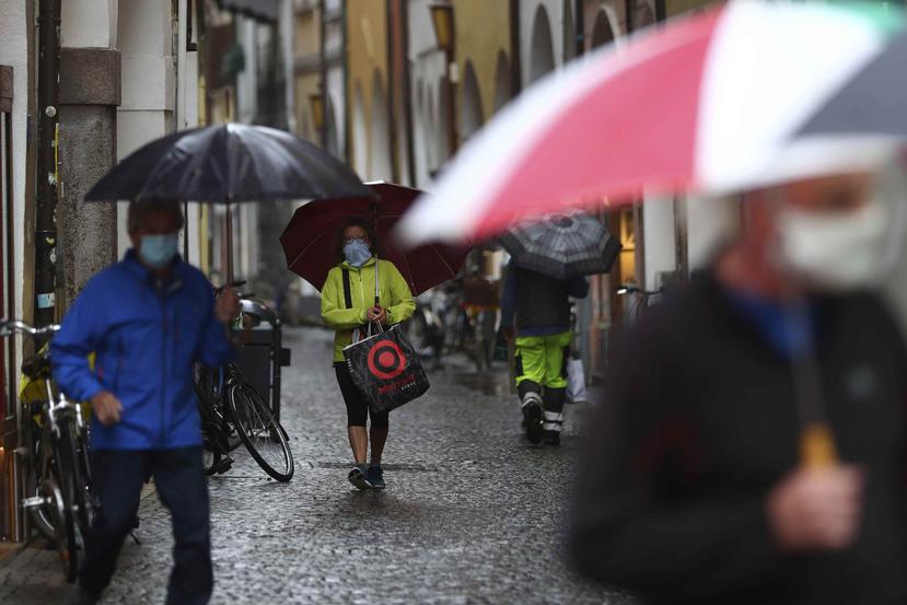 Personas utilizan mascarillas protectores mientras caminan por las calles de Bozen, Italia. (AP)