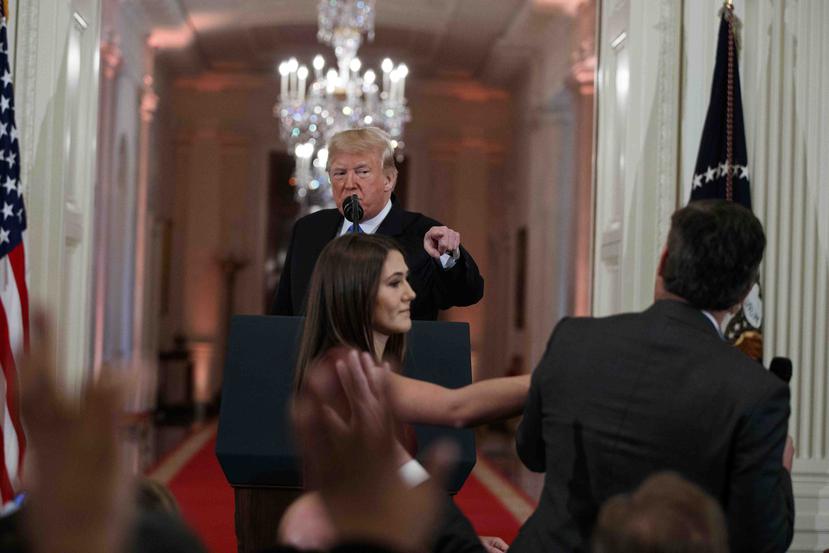 Una becaria intenta quitarle el micrófono a Acosta. (AP)
