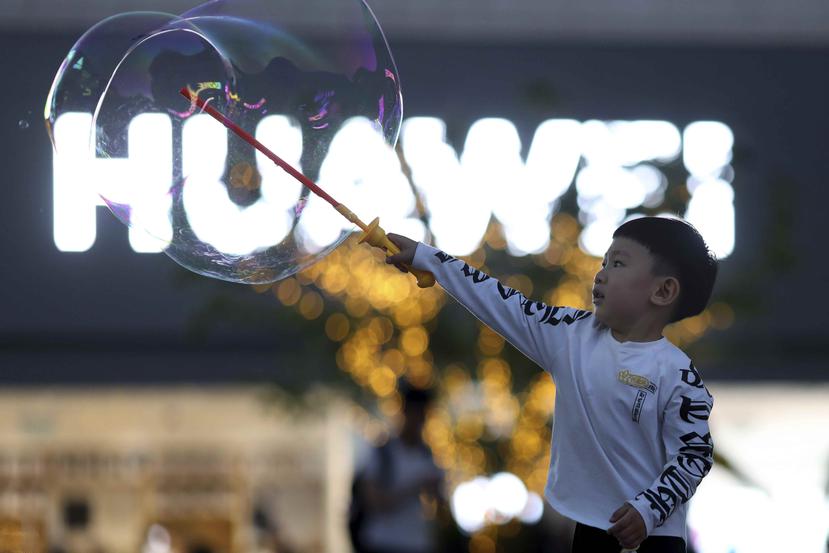 En esta imagen, tomada el 20 de mayo de 2019, un ni o juega con pompas de jab n cerca del logo del gigante tecnol gico chino Huawei, en Beijing. (AP)
