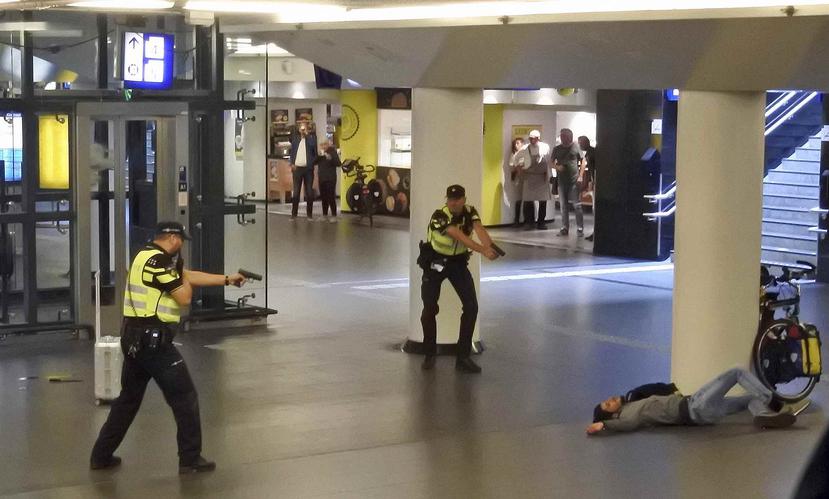 Dos policías holandeses apuntan sus armas hacia un hombre abatido a disparos por los agentes después de que éste apuñaló a dos personas en la estación central de trenes en Amsterdam, el viernes 31 de agosto de 2018. (AP)