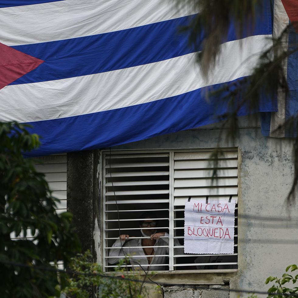 Yunior García Aguilera, dramaturgo y uno de los organizadores de una marcha de protesta, junto a un letrero que dice "Mi casa está bloqueada", que colgó en una ventana de su residencia, en La Habana, Cuba.