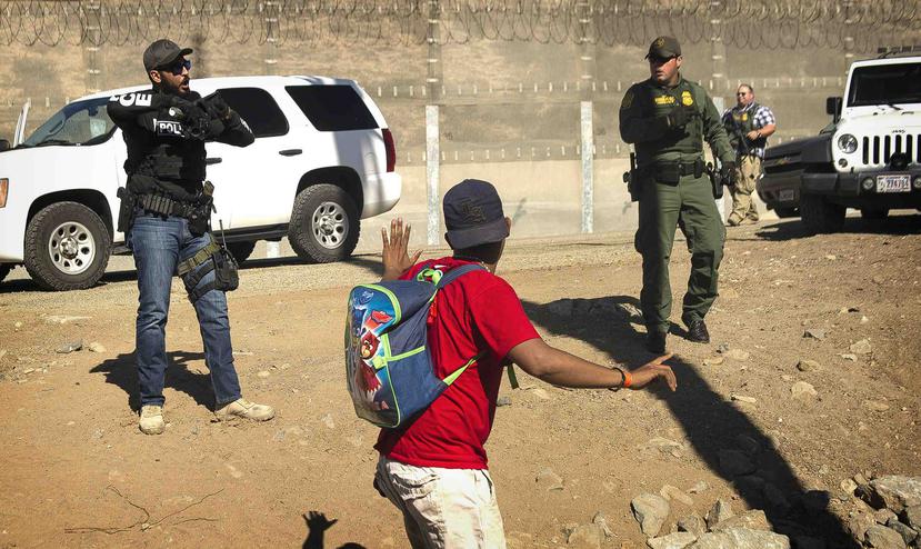 Un migrante centroamericano es detenido por agentes estadounidenses que le ordenaron volver al lado mexicano de la frontera, después de que un grupo de migrantes rebasó a la policía mexicana en el cruce. (AP)