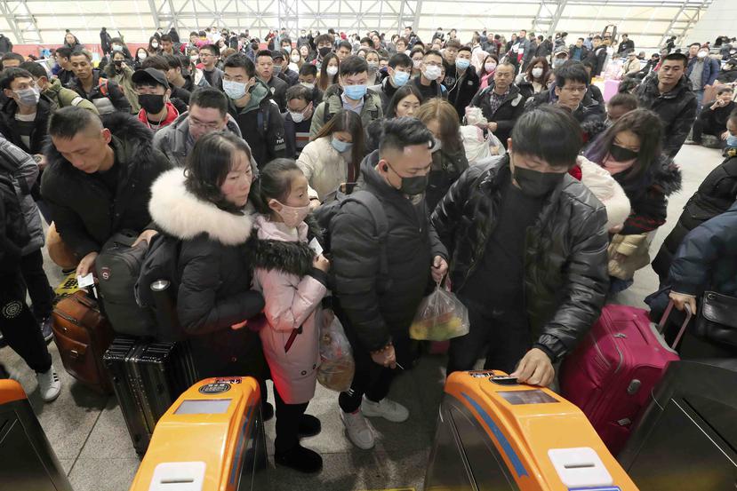 Viajeros equipados con máscaras hacen fila ante los tornos para acceder a una estación de tren en Nantong, China. (AP)