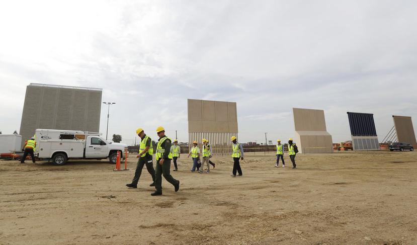 Ingenieros y operarios caminan frente a los prototipos de muro fronterizo (AP).