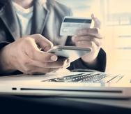 Un hombre sostiene una tarjeta de crédito en la mano mientras realiza una transacción electrónica.