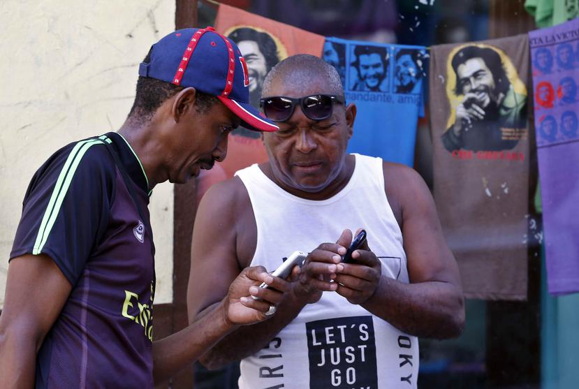Dos clientes de Etecsa intentan conectarse al Internet mediante sus teléfonos móviles en Cuba. (EFE / Ernesto Mastrascusa)
