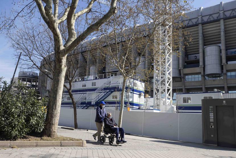 Dos hombres transitan protegidos con mascarillas frente al estadio Santiago Bernabeu, en Madrid. (AP)
