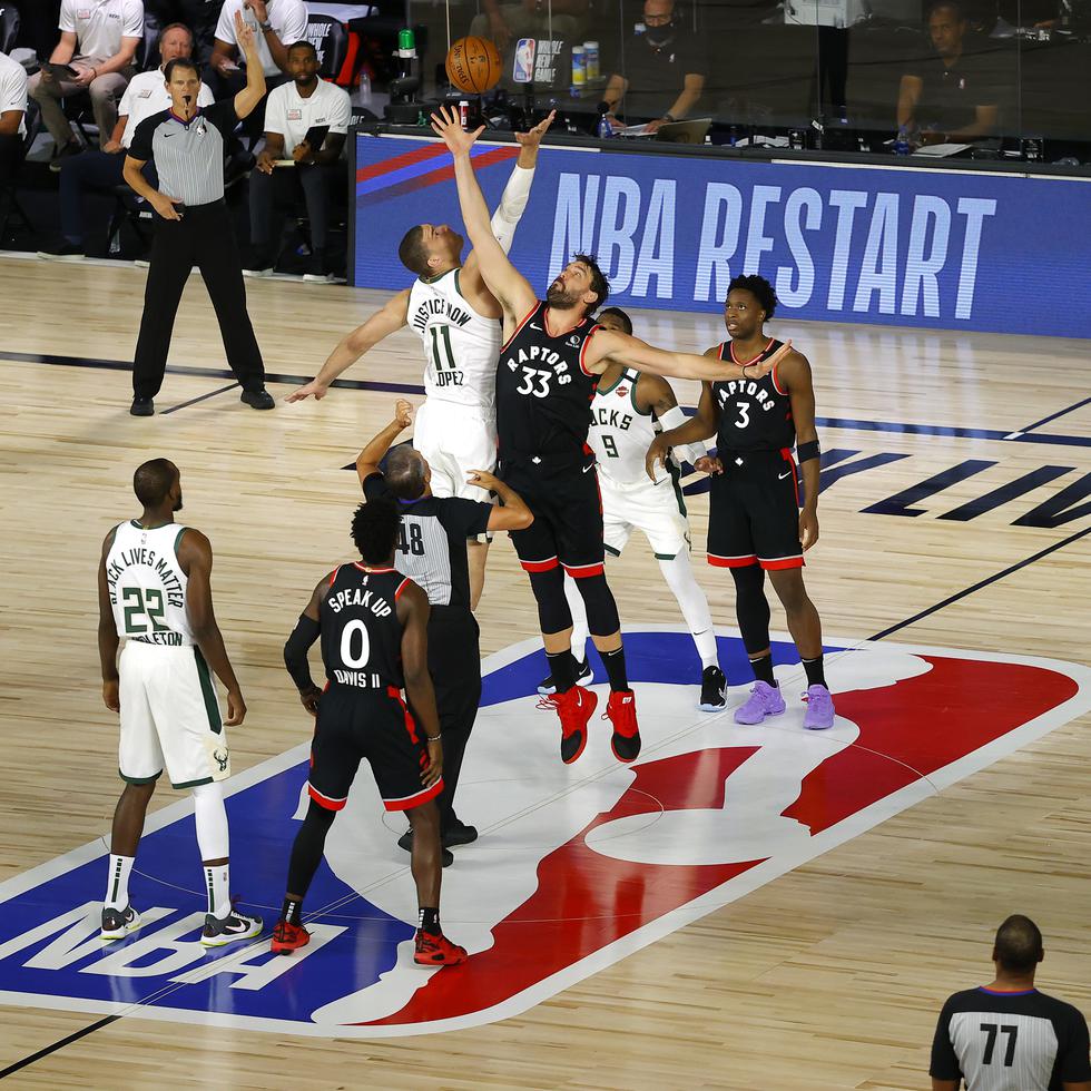Marc Gasol (33) de los Raptors de Toronto y Brook Lopez (11) de los Bucks de Milwaukee saltan por el balón al inicio del partido de la NBA, el lunes 10 de agosto de 2020, en Lake Buena Vista, Florida. (Mike Ehrmann/Pool Photo vía AP)
