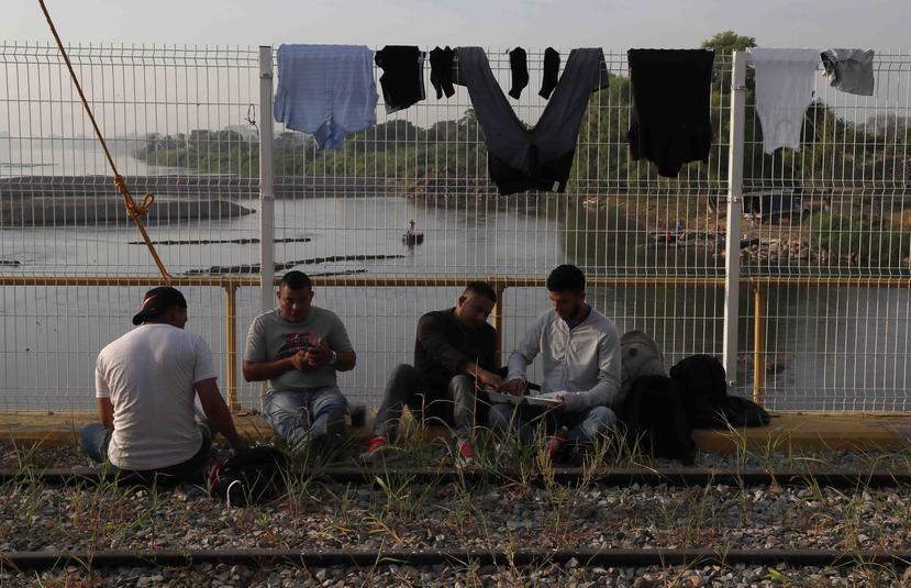 Un grupo de inmigrantes esperan por el permiso para entrar a México. (AP)