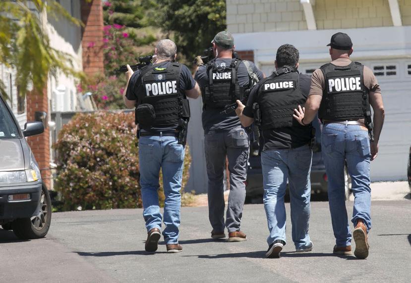 Agentes de policía de San Diego fuertemente armados se acercan a la casa donde se cree vivía John T. Earnest, de 19 años, sospechoso del tiroteo en una sinagoga en Poway, California. (John Gibbins / The San Diego Union-Tribune vía AP)