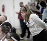 En esta fotografía del miércoles 4 de noviembre de 2020, una aspirante republicana a las elecciones (derecha) observa a los inspectores electorales mientras examinan una papeleta durante el conteo de votos en la junta central de recuento de Detroit.
