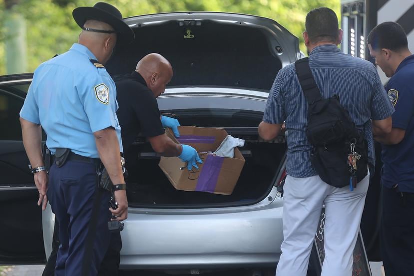 Agentes investigan pertenencias en el baúl del vehículo de un hombre asesinado en Loíza.