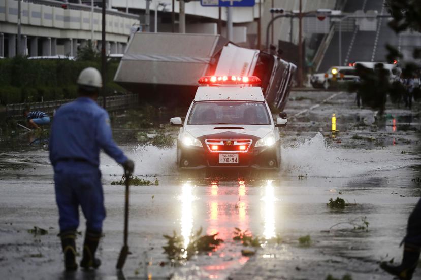 Un coche de policía avanza por una carretera anegada tras el paso del potente tifón Jebi por Osaka, al oeste de Japón, el 4 de septiembre de 2018. (Kota Endo/Kyodo News via AP)