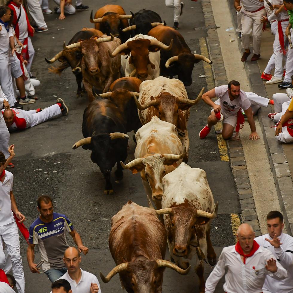 Toros corren entre los participantes del primer encierro de las Fiestas de San Fermín en la ciudad de Pamplona, España, el viernes 7 de julio de 2023.