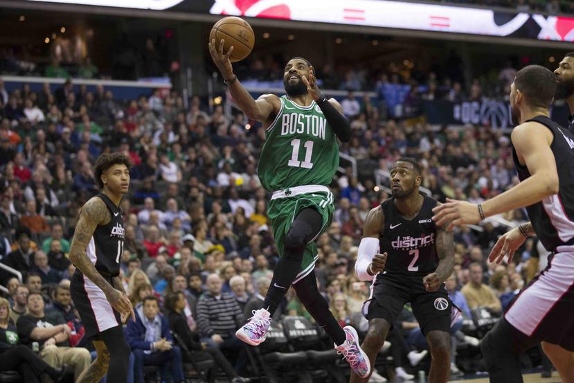 Kyrie Irving, de los Celtics de Boston, dispara entre Kelly Oubre Jr., (izquierda) y John Wall (2), de los Wizards de Washington. (AP)